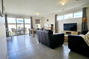 a living room with a couch and a television and a table at Comfort on Mozart in Shepparton