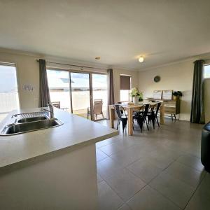 a kitchen with a sink and a table with chairs at Comfort on Mozart in Shepparton