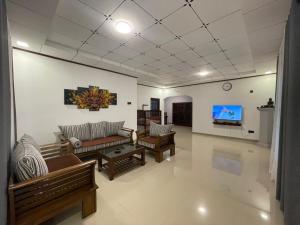 a living room with couches and a flat screen tv at Villa One Hikkaduwa in Hikkaduwa