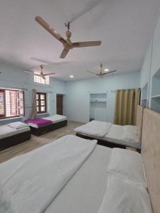 a room with two beds and a ceiling fan at Jodhpur House Mount Abu in Mount Ābu