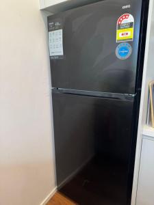 a black refrigerator in a kitchen with stickers on it at De'Vine Escape in Dixons Creek