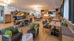 a restaurant with wooden floors and tables and chairs at Rittis Alpin Chalets Dachstein-inklusive Sommercard! in Ramsau am Dachstein