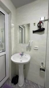 a white bathroom with a sink and a mirror at Al-Xorazmiy Hotel in Urganch