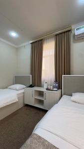 a hotel room with two beds and a window at Al-Xorazmiy Hotel in Urganch