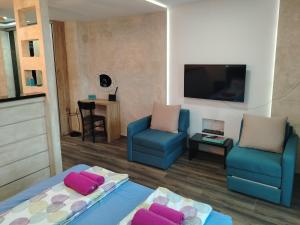 a living room with two blue chairs and a tv at Apartman Harmony 5 in Banja Koviljača