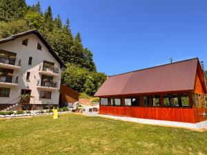 a building with a red roof next to a house at Pensiunea Emanuel in Gârda de Sus +55 photos