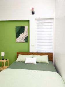 a bedroom with a large bed with a green wall at Lapausa Homestay in Kỳ Vĩ