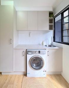 a white kitchen with a washing machine and a sink at Rainbow House in Rainbow Beach