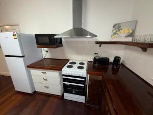 a small kitchen with a stove and a refrigerator at Huge comfy 4br home near CBD in Geraldton