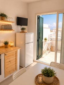 a kitchen with a table and a refrigerator and a balcony at Poésia in San Foca