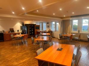 ein Restaurant mit Holztischen und -stühlen und Fenstern in der Unterkunft Hotel Wassberg - Self-Check-in in Forch