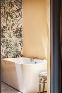 a bath tub in a bathroom with a tropical wallpaper at ATELIER5 Suites in Ermoupoli