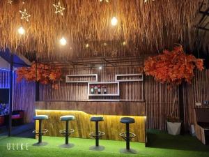 a bar with four stools in a room with trees at Tiki Pool Pattaya in Ban Nong Pla Lai