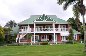 a large red house with a green roof at Mount Edgecombe Estate Lodge in Mount Edgecombe
