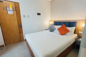 a bedroom with a white bed with orange and blue pillows at Coast Wise Hotel Dumaguete in Dumaguete