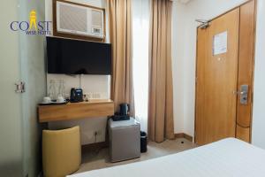 a room with a bed and a desk with a tv at Coast Wise Hotel Dumaguete in Dumaguete