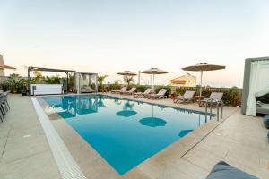 a swimming pool with chairs and umbrellas on a building at Arfna Grand Villa in Afantou