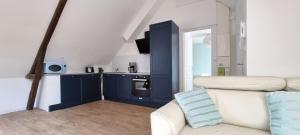 a living room with a white couch and a kitchen at Le Charmant in Dieppe