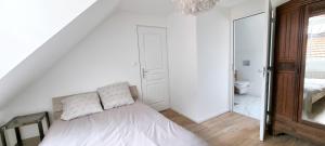 a white bedroom with a bed and a bathroom at Le Charmant in Dieppe