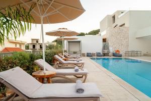 a pool with chairs and umbrellas next to a swimming pool at Arfna Grand Villa in Afantou