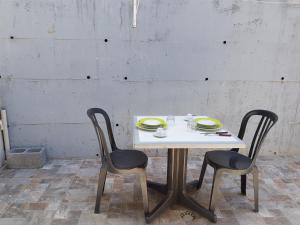 a white table with two chairs and plates on it at L'ANNEXE 66 , Saint Denis Centre Ville , à 200 m de la Rue Piétonne , du Petit Marché et du Leader Price , sur une rue calme, PARKING GRATUIT sur la rue in Saint-Denis
