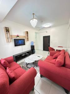 a living room with two red couches and a tv at BMW Buxton point Apartment in Mombasa