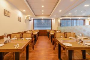 a restaurant with wooden tables and chairs and a large window at Foxoso The BMK - A Corporate Hotel in New Delhi