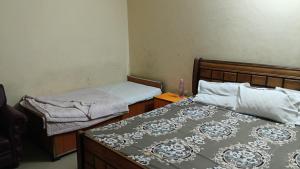 a bedroom with two beds and a night stand with a bedskirts at Shubharohi stay in Chhatikara
