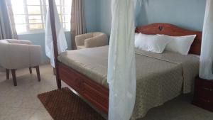 a bedroom with a bed and a chair and window at Summer Oasis in Kitui