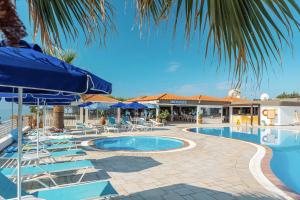 a swimming pool with chairs and umbrellas next to a resort at Elvita beach hotel in Lartos