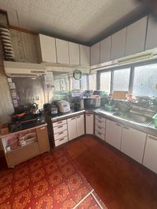 a kitchen with white cabinets and a sink at 2つの温泉が徒歩圏内にある一棟貸し古民家民宿Honjo no ie駐車場4台無料最大9名宿泊可能 in Yurihonjo