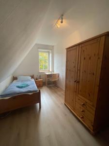 a bedroom with a bed and a large wooden cabinet at Gästehaus Wedework in Wedemark