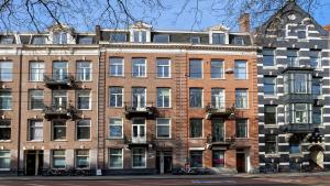 a large brick building with a clock on top of it at Marnix360apartments-Suites Jordaan in Amsterdam