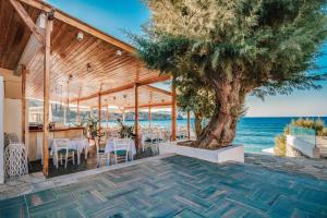 a patio with a tree and tables and chairs at Istron Bay Hotel in Istro