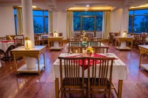 a dining room with tables and chairs and windows at The Nature Residency - A Riverside Resort in Leh in Leh