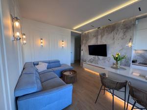 a living room with a blue couch and a tv at Aqua Concept Apartment Sol Marina in Wiślinka