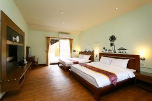 a bedroom with two beds and a flat screen tv at Ruisui Palm Lakes B&B in Ruisui