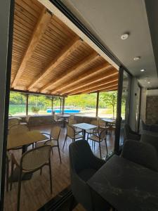 a restaurant with tables and chairs and windows at Guest House Besi in Fierzë