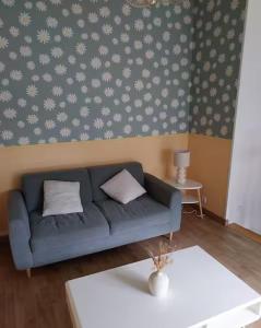a living room with a blue couch with white pillows at Maison au calme 2 chambres centre de Caen in Caen