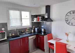 a kitchen with red cabinets and a clock on the wall at Maison au calme 2 chambres centre de Caen in Caen