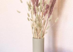 a white vase with flowers in it next to a wall at L'escale - proche Homme de Fer in Strasbourg