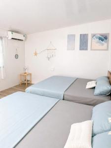 two beds in a room with white walls at La Pausa Homestay in Kỳ Vĩ