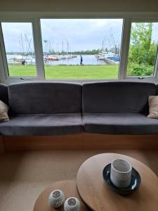 a living room with a couch and a table at Stacaravan met schitterend uitzicht over het meer, in Friesland! Op de 5-sterren Camping de Kuilart met Zwembad! in Koudum