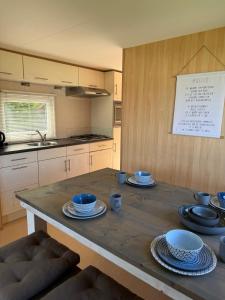 a kitchen with a wooden table with blue dishes on it at Stacaravan met schitterend uitzicht over het meer, in Friesland! Op de 5-sterren Camping de Kuilart met Zwembad! in Koudum