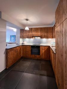 a kitchen with wooden cabinets and a black dishwasher at Evasion Alpine in Crans-Montana