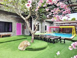 a garden with a tree and a pool with benches at Tiki Pool Pattaya in Ban Nong Pla Lai