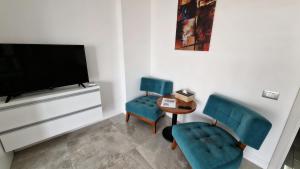 a living room with two blue chairs and a tv at White Tower Mamaia Beach 505 in Mamaia