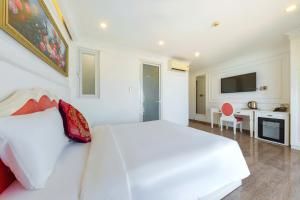 a white bedroom with a white bed and a kitchen at Michael Hotel in Nha Trang