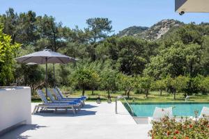 a group of chairs and an umbrella next to a pool at Casadi Luxury Villa in Ialysos