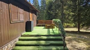 a porch of a building with a bench and grass at Chata Bambi, Tatranská Štrba pri zubačke in Štrba